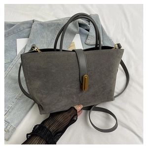 Detailed macro of dark grey frosted suede handbag with golden metal hardware and strap