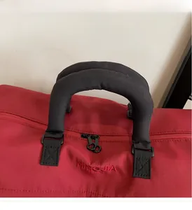 Close-up of red travel bag featuring padded black handles and durable nylon stitching