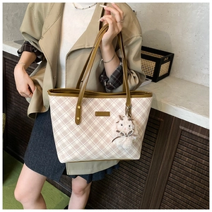 Detail of checkered tote bag with brown leather straps and cute rabbit charm