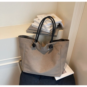 Detail of khaki canvas tote bag with black round handles and stylish knot decorative elements