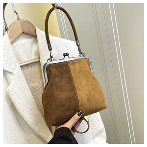 Close-up of vintage vertical two-tone suede shell bag with metal frame and top handle