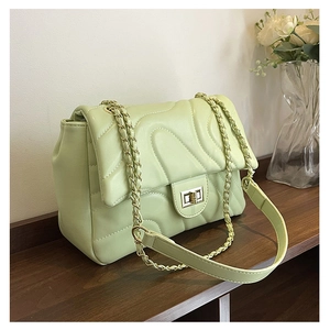 Close-up of light green quilted shoulder bag featuring gold chain and turn-lock detail