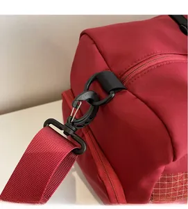 Close-up of durable red nylon sports bag with adjustable shoulder strap and black hook detail