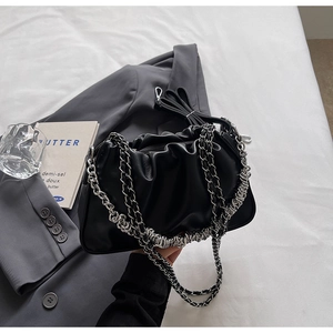 Detail of black pleated dumpling bag featuring silver chain strap and leather material