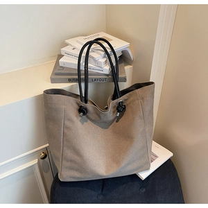 Close-up of khaki canvas tote bag with black knotted handles on blue velvet bench
