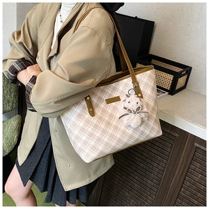 Detail of pink plaid tote bag featuring a brown leather handle and cute rabbit plush charm
