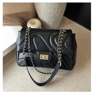 Close-up of wavy quilted pattern and golden turn-lock on the black chain crossbody bag