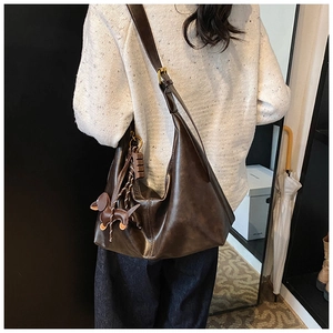 Detail of dark brown vintage underarm bag with puppy charm and adjustable strap