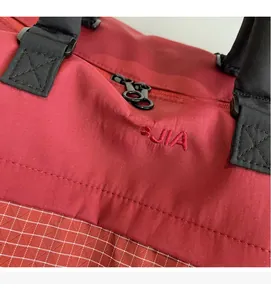 Close-up of red nylon fitness bag showing embroidery and white checkered bottom texture