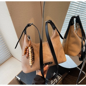 Détail du sac demi-lune en daim kaki avec breloque en bois ethnique et étiquette en métal