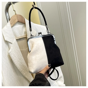Detail of black and white suede handbag with metal clasp and vintage round handle