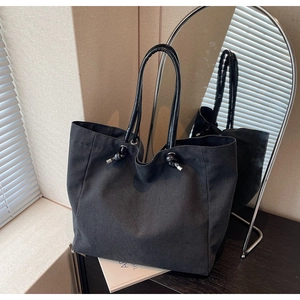 Close-up of black canvas tote bag with knot detail and silver metal hardware