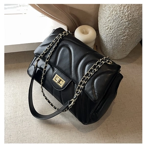 Detail of black chevron quilted leather crossbody bag with golden chain and turn-lock