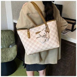 Detail showing checkered tote bag with plush bunny charm and brown leather straps