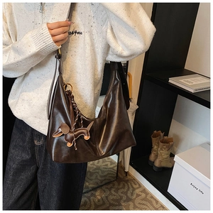 Detail of a dark brown soft leather hobo bag with a cute dachshund puppy pendant accessory