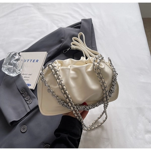 Detail of cream pleated cloud bag with chunky silver chain on modern minimalist setting