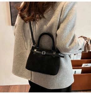 Close-up of matte black suede tote bag with silver buckle and crossbody strap detail