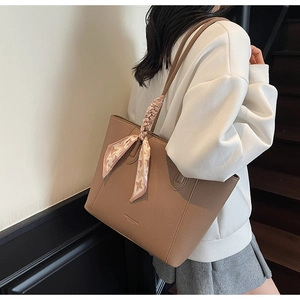 Close-up of brown pebbled leather tote bag with a chic houndstooth silk scarf decoration