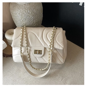 Detail of cream quilted crossbody bag with gold chain strap and wave stitching texture