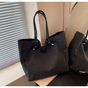 Detail of black canvas tote bag with leather handle and knot design in elegant setting