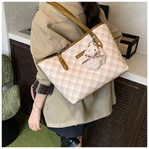 Detail view of pink plaid tote bag with brown leather trim and cute sheep charm accessory