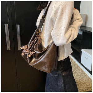 Detail of vintage brown hobo bag featuring dog charm and woven tassel strap decoration