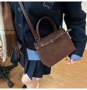 Brown retro matte leather bucket bag worn with a navy blue vintage outfit on wooden floor