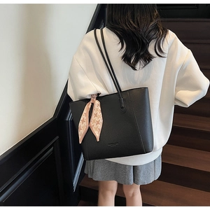 Detail of black lychee leather tote bag featuring a decorative houndstooth silk scarf