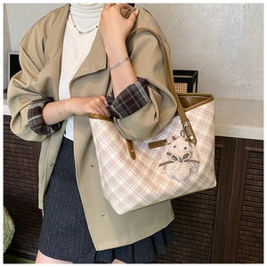 Detail of checkered tote bag with brown leather trim and cute white plush lamb pendant