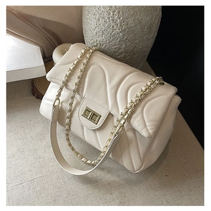 Detail of cream quilted crossbody bag with V-shaped stitching and gold chain strap
