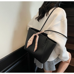 Detail of black pebbled leather tote bag with elegant houndstooth silk scarf decoration
