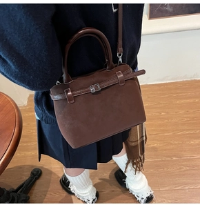 Detail of dark brown matte suede bucket bag with leather strap and metal buckle buckle