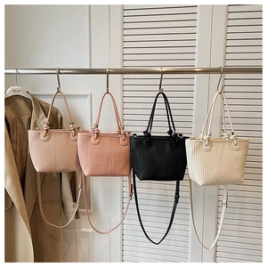 Detail view of woven textured tote bags in four neutral colors hanging on a metal rack