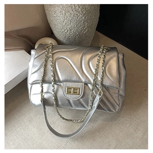 Macro shot of silver quilted chain bag with gold metal twist lock and wavy stitching