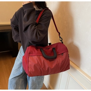 Detail view of red travel bag with white checkered pattern and reinforced handles