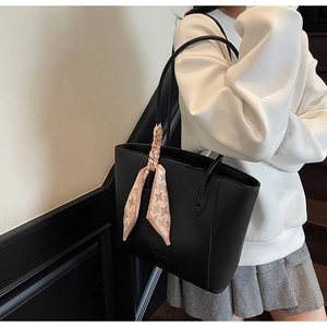 Black lychee leather tote bag with pink houndstooth scarf on model in stairwell