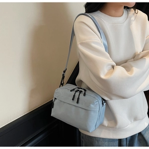 Side view of model wearing a light blue nylon crossbody camera bag with wide strap