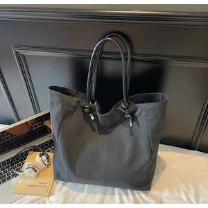 Detail of minimalist black canvas tote bag with knot handle and silver metal accents