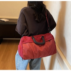 Detail of red checkered travel bag featuring adjustable shoulder strap and side zipper pocket