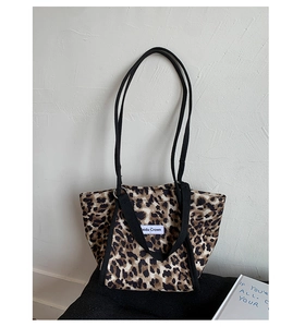 Détail du sac fourre-tout en toile à motif léopard avec bandoulière noire et étiquette