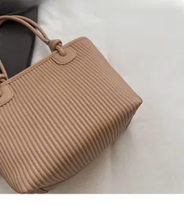 Detail of light brown bucket bag featuring vertical pleats and textured PU leather finish