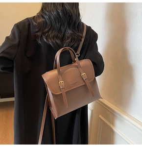Detailed view of a vintage brown leather backpack worn with a stylish black coat