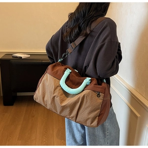Rear view of a model carrying the large checkered travel tote with mint green handles