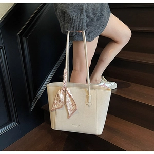 Detail of beige lychee texture leather tote bag with elegant pink houndstooth scarf handle