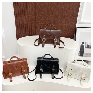 Detail view of four vintage leather backpacks in brown, black, and beige with metal buckles