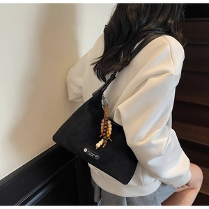 Détails d'un sac bandoulière noir mat avec perles en bois et logo métallique rétro