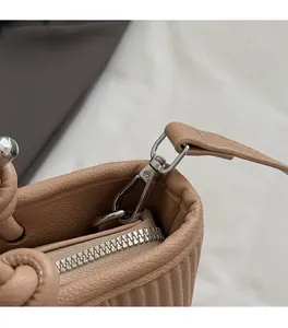Detail shot of silver metal hook and leather grain texture on a camel crossbody bag
