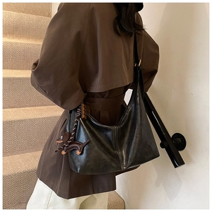 Detail of black leather hobo bag with contrast stitching and dachshund charm on model