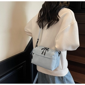 Back view of light blue nylon crossbody bag styled with casual beige sweatshirt