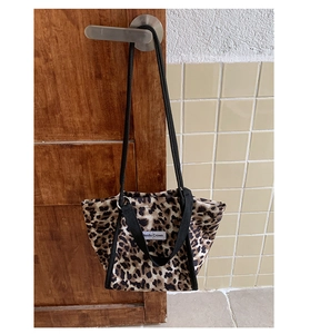 Détail du sac cabas en toile à motif léopard avec doubles poignées noires et étiquette logo
